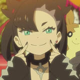 A screenshot of marnie from the Pokémon Anime, using her two index fingers to form a smile on her face. Morpeko is sitting on her shoulder.